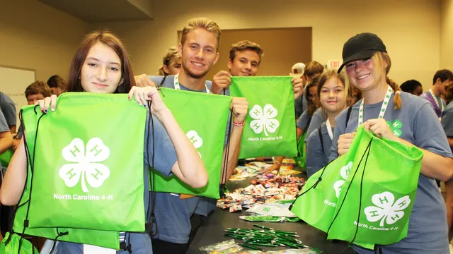 4-H members hold green drawstring bags while assembling care packages during a hands to service project at 4-H Congress.