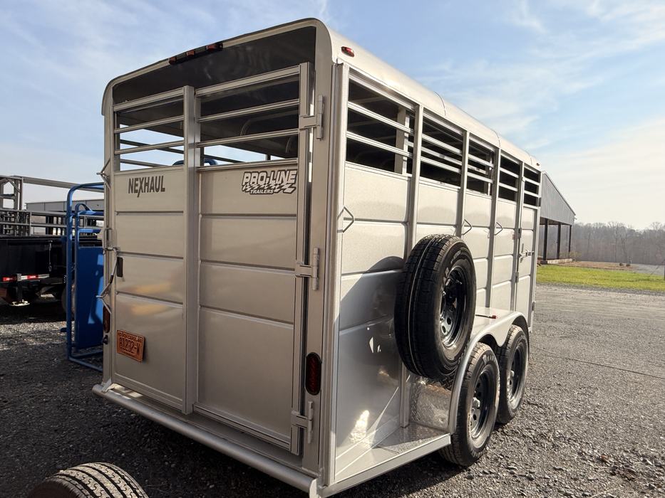 The rear view of a silver NexHaul Pro-Line livestock trailer, showing the large swinging gate and slatted upper panels. A spare tire is mounted on the side.