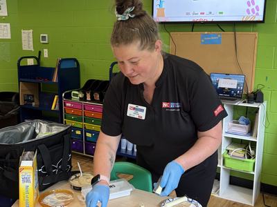 Jamie preparing a snack for youth in a classroom