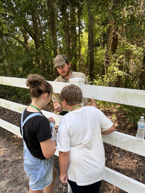 Two 4-H members learning from NC Forestry about Tree ID. Inspecting different parts of the tree.