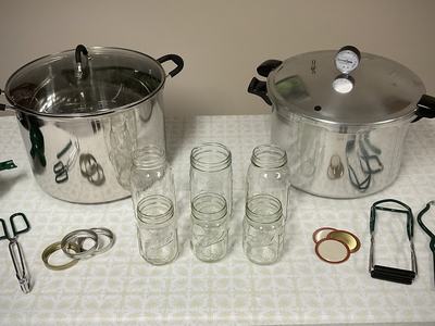 dial gauge canner and weighted canner on stove tops with canning jars and other canning equipment