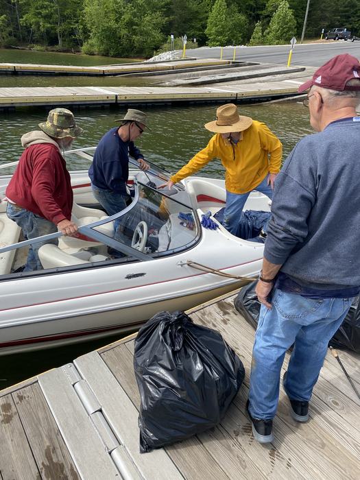 four volunteers passing a garbage bag out of a boat into the dock