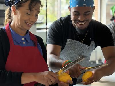 staff in kitchen wearing aprons and zesting lemons