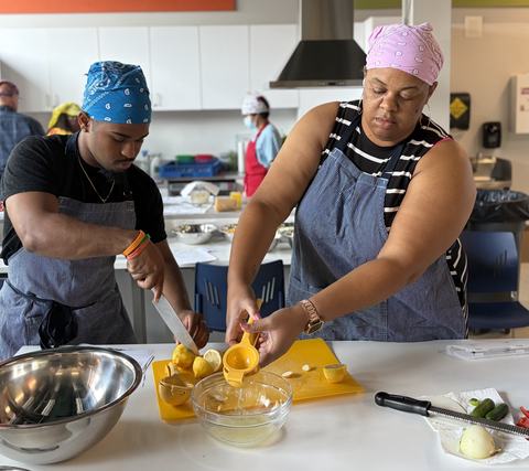 staff in kitchen wearing aprons and  squeezing lemons