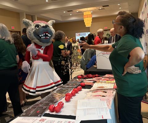 Shewana behind table at event with Ms. Wuf