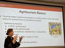 Woman stands in front of slide explaining Agritourism Basics.