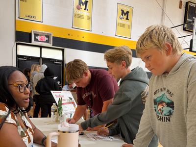 Adult volunteer talking with youth at booth