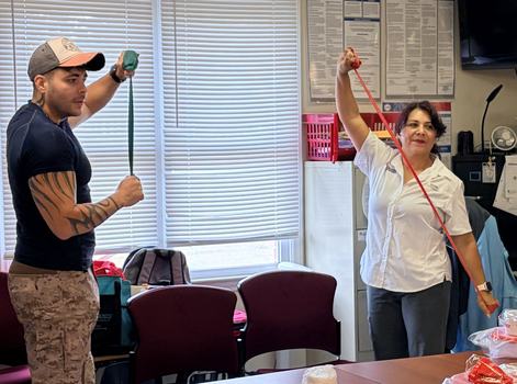 Patty and volunteer demonstrating how to do exercise with resistance bands