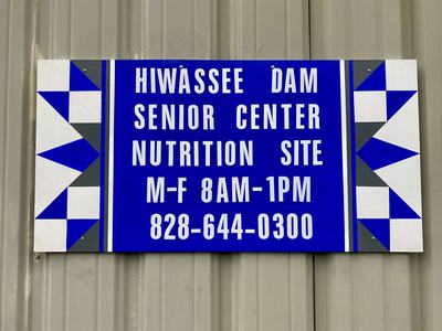 Photo of a sign on an exterior wall. Text reads:
Hiwasse Dam Senior Center Nutrition Site - M-F 8AM-1PM - 828-644-0400