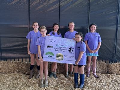 Pamlico County 4-H Dairy Project participants hold a sponsor appreciation banner recognizing supporters of the 2026 Craven/Pamlico Dairy Project.