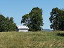 Photo of a dry hayfield, with an old tobacco barn in the background