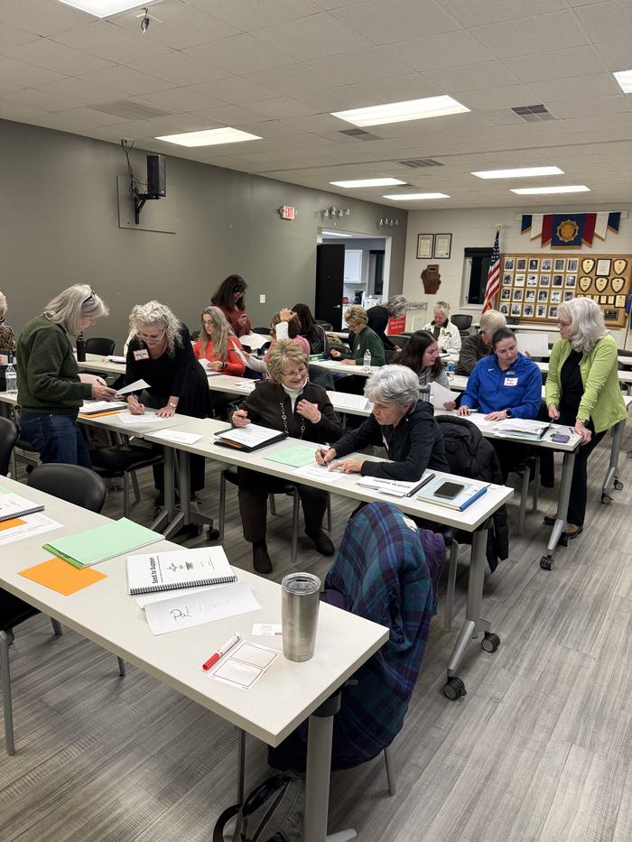 Participants seated at tables working through Seed to Supper gardening materials and worksheets during a class session at the Clay County Center.