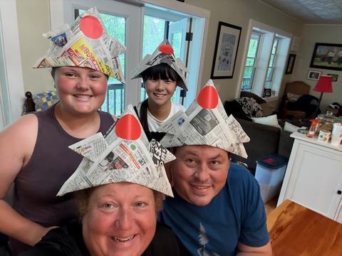 A family is pictured wearing large origami samurai hats made from newspaper.