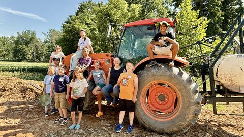 Youth group posing on an orange tractor
