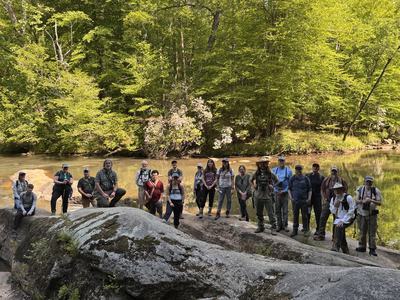 Photo of naturalist class standing on rocks beside a river