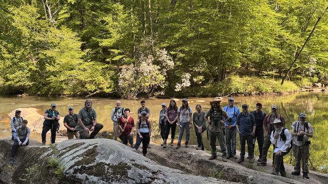Photo of naturalist class standing on rocks beside a river