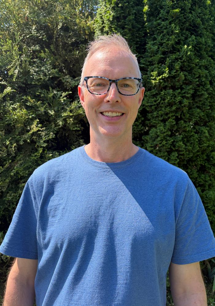 Greg Stivland, a man wearing glasses and a blue shirt.