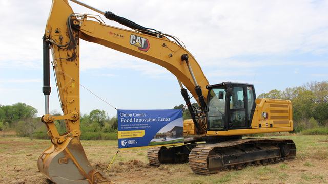 Banner announcing the Union County Food Innovation Center hanging from piece of heavy equipment
