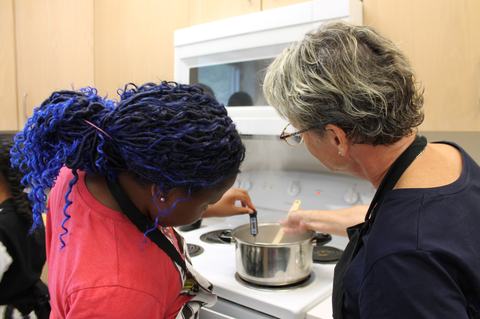 EFNEP educator and camper are testing the temperature of the meat in pot.