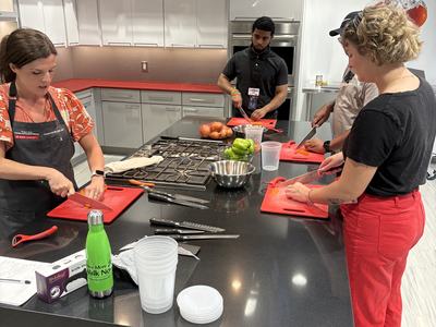 staff standing at a countertop learning to cut vegetables