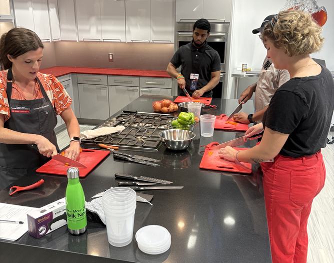 staff standing at a countertop learning to cut vegetables
