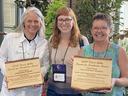 Three women display wooden plaques bearing the inscription "2023 David Gibby Search for Excellence Award."