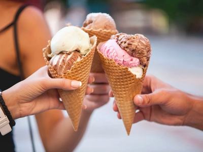 Hands holding ice cream cones.