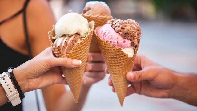 Hands holding ice cream cones.
