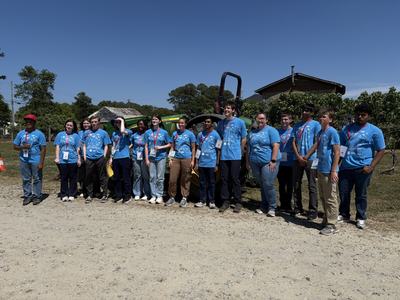 group of students in blue shirts posing for photo at farm