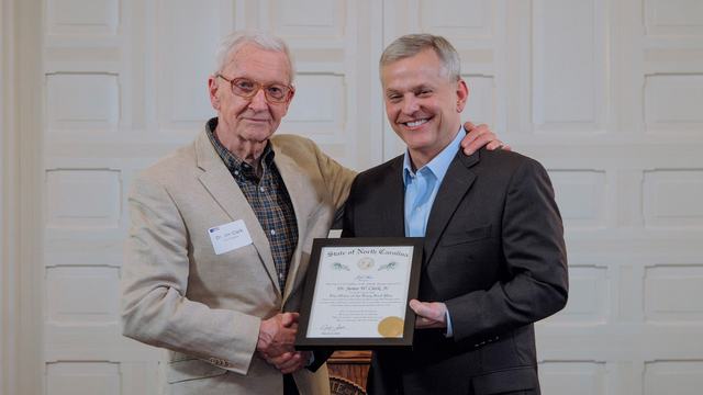 Dr. Jim Clark stands with Governor Josh Stein during his induction into the Order of the Long Leaf Pine at the governor’s mansion.