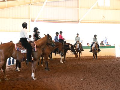 A group of exhibitors in the covered arena at the 2025 NC State 4-H Horse Show