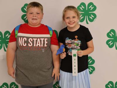 Two 4-Hers posing for a picture in front of banner