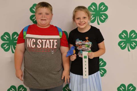Two 4-Hers posing for a picture in front of banner