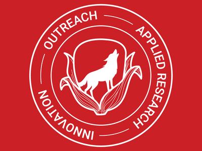 Red background with logo of the NCSU Corn Agronomy Program featuring a corn kernel surrounded by corn leaves. Inside the kernel there is the silhouette of a howling wolf.