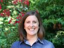 A profile photo of NC State Extension Interim Assistant Director of Youth Programs Liz Driscoll smiling, with flowering shrubbery in the background.