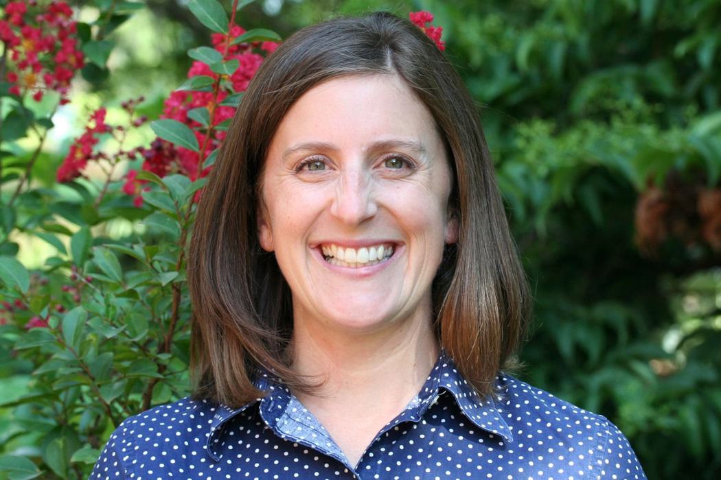 A profile photo of NC State Extension Interim Assistant Director of Youth Programs Liz Driscoll smiling, with flowering shrubbery in the background.