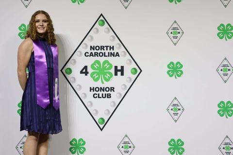 Honor Club member posing beside banner
