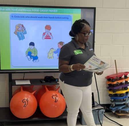 Lynnell standing in front of a screen teaching in a first grade classroom
