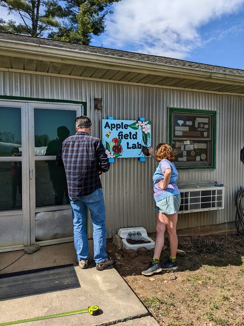 Two people hanging sign on building