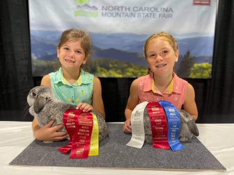 Two 4-Hers with their show rabbits and ribbons.