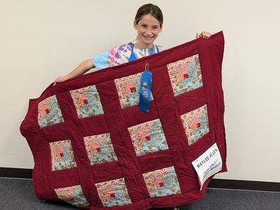 girl and a quilt with a blue ribbon