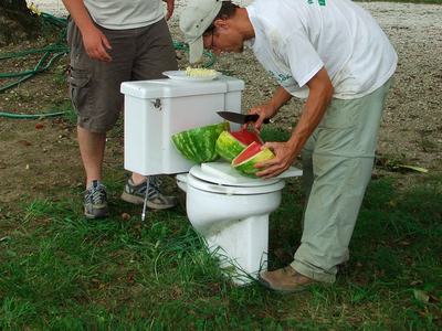 People preparing food on old toilet outdoors
