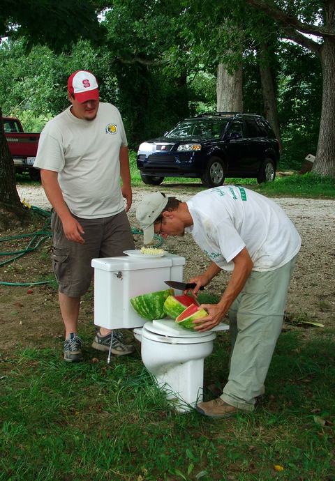 Two people preparing food on old toilet in yard