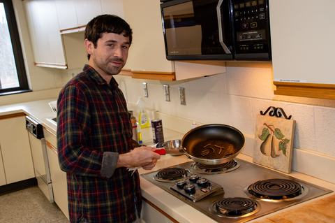 Person holding frying pan full of caterpillars