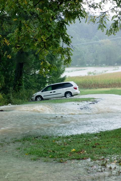 Van in floodwaters beside line of trees