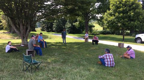 People sitting at socially-distanced intervals in grassy lawn