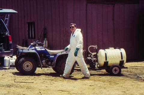 Man in protective spray suit with all-terrain vehicle