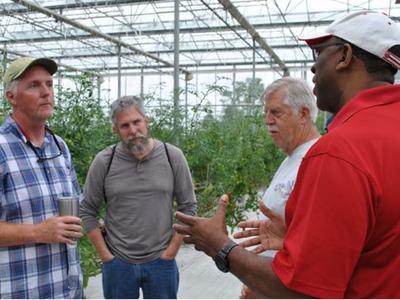 Four people seeking to begin an agricultural business tour a local greenhouse production system