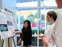 A North Carolina 4-H'er named Kira Wiguna points to a graph on her research poster