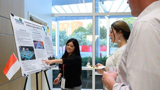A North Carolina 4-H'er named Kira Wiguna points to a graph on her research poster